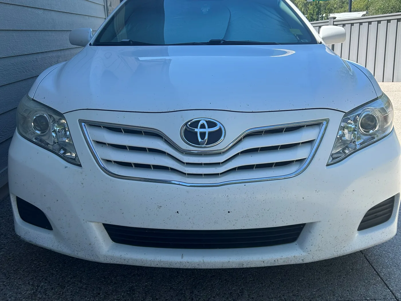 The same white Camry from the front after restoration, both lenses clear with the projectors visible