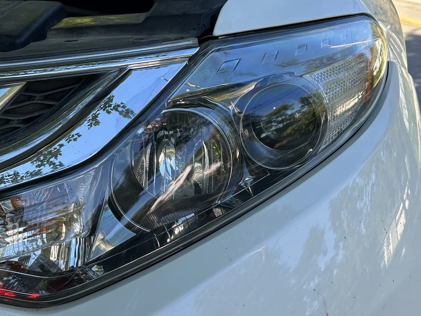 The same Murano headlight after restoration, the lens clear with both projectors, the chrome trim and the reflector texture sharply visible