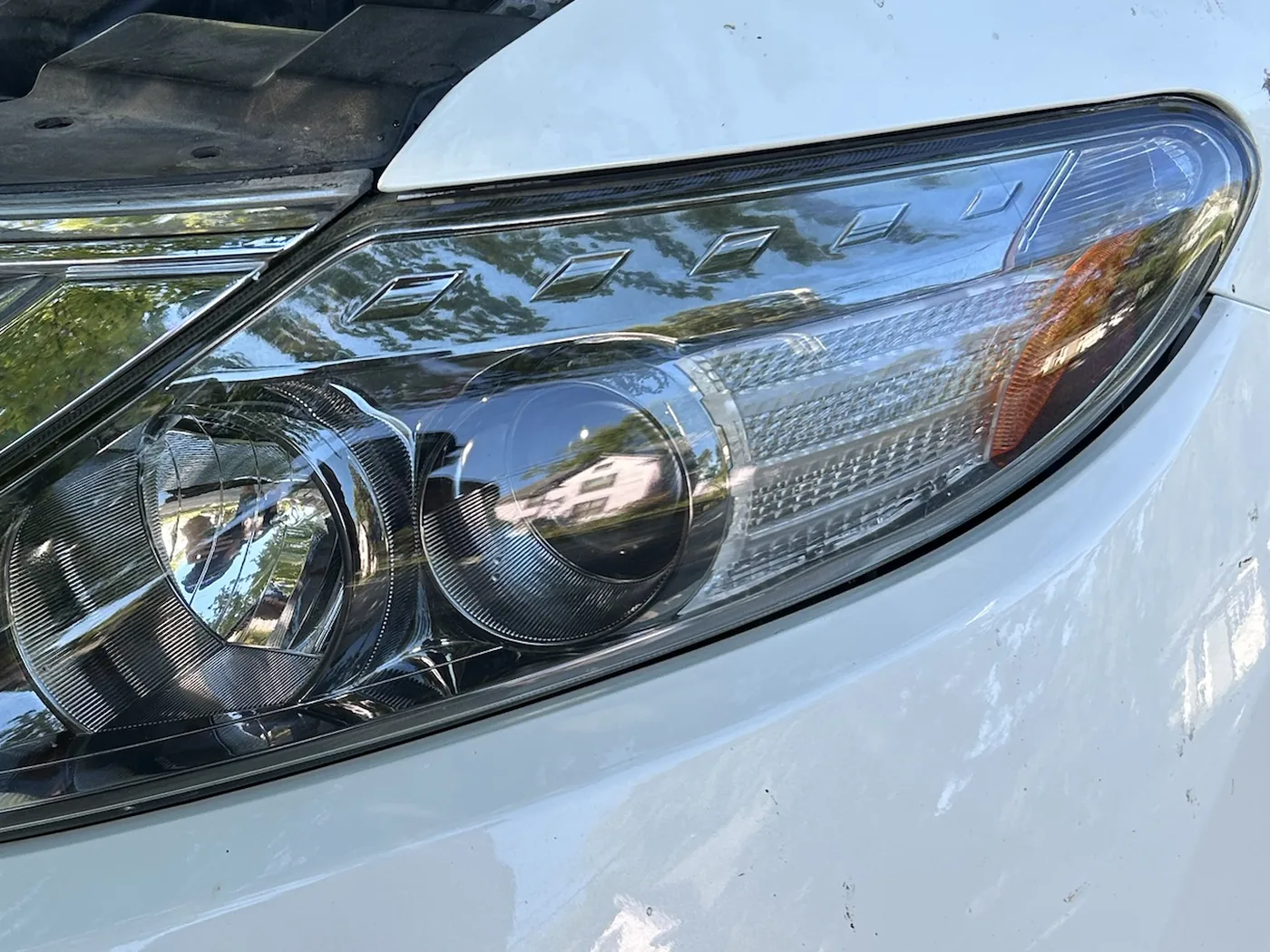 The same headlight at eye level after restoration, glossy and fully transparent against the same paint