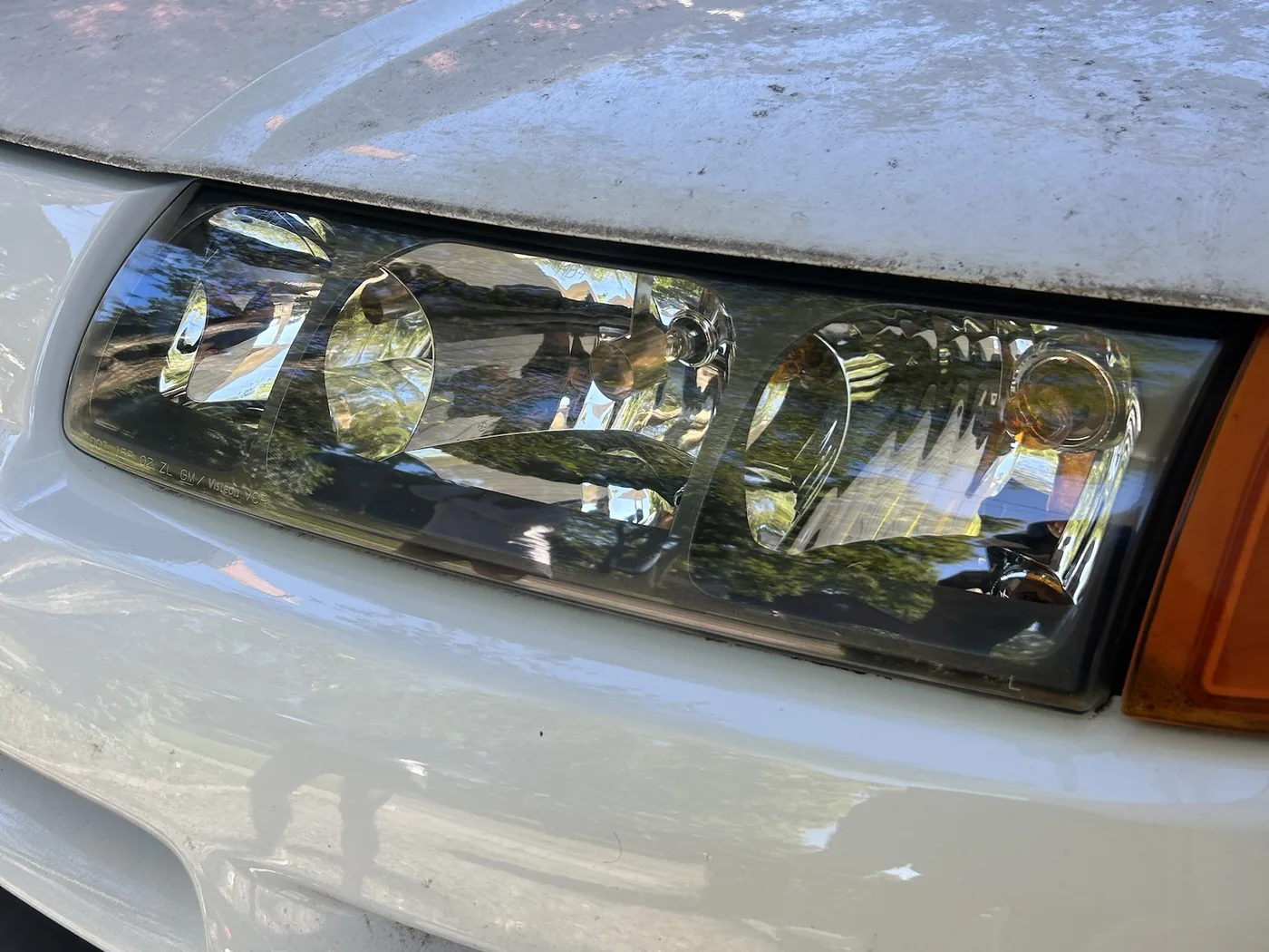 The same Saturn VUE headlight after restoration, the lens fully clear with all three reflector chambers and the bulbs sharply visible