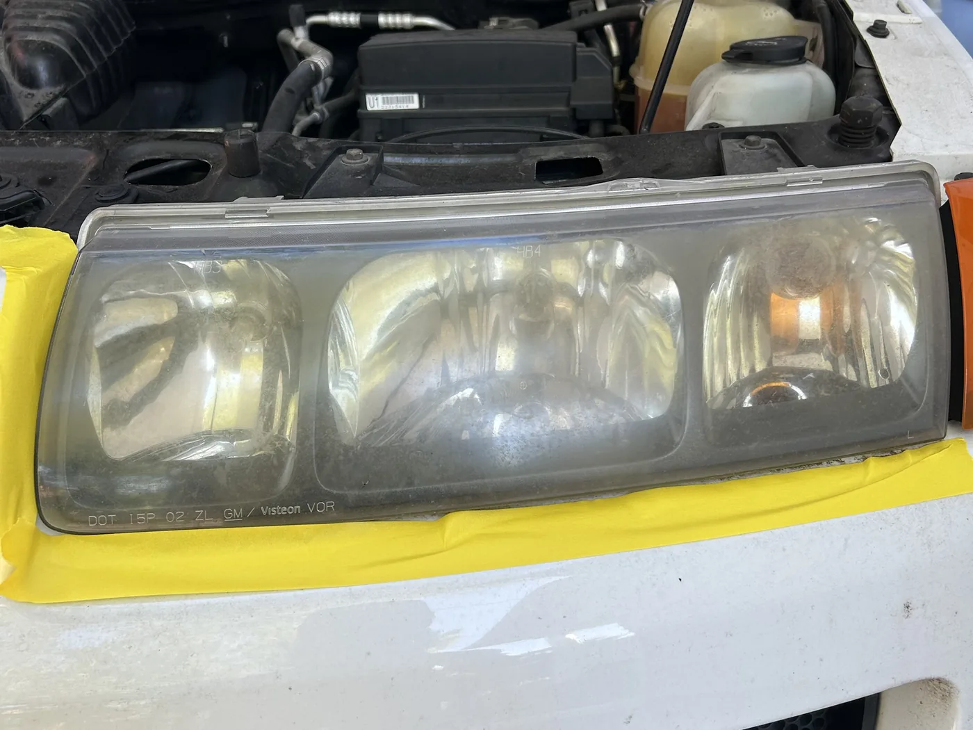 Close-up of the same Saturn VUE headlight before restoration, the whole lens face fogged a dull yellow-brown